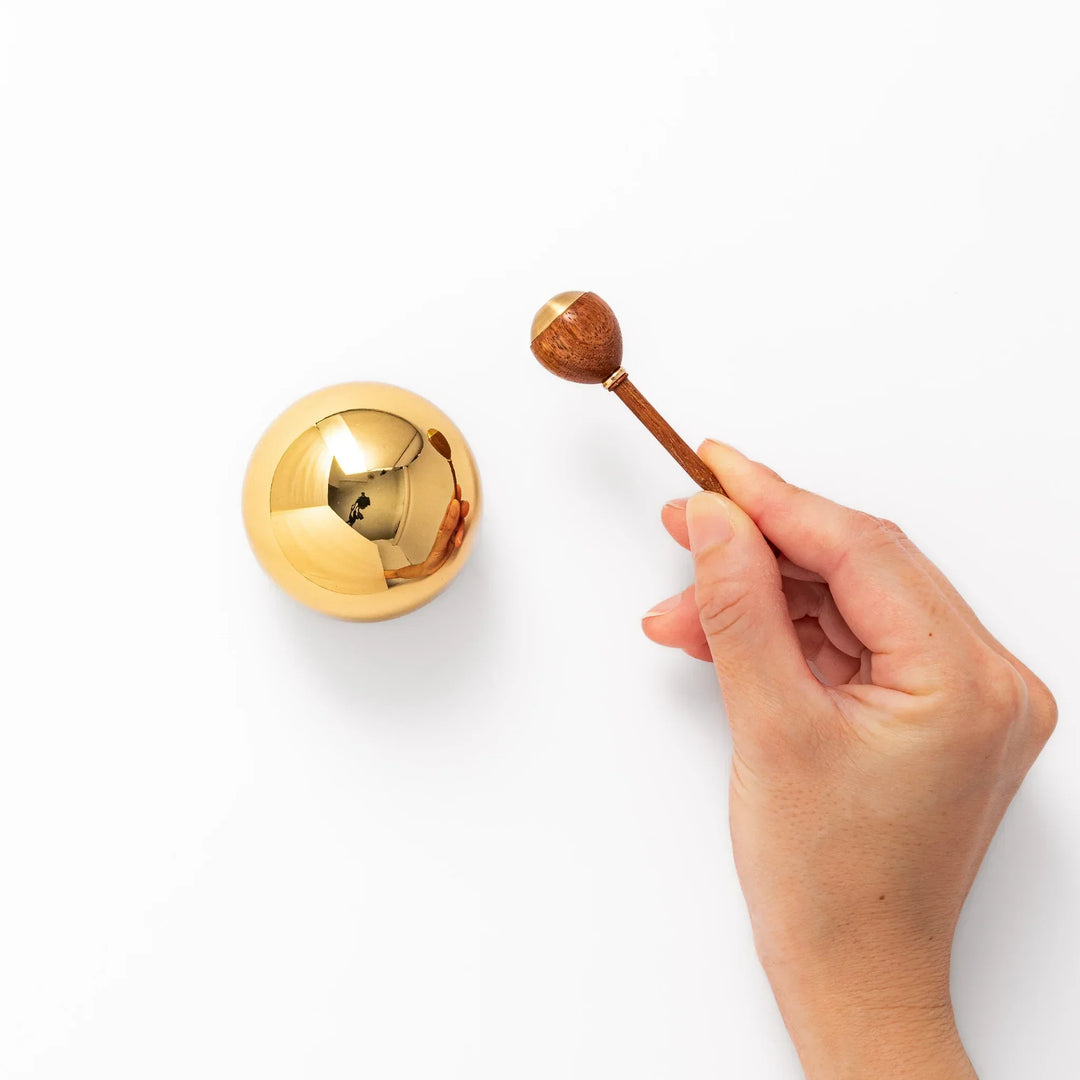 Japanese meditation and prayer chime with golden dome bell and wooden striker for mindfulness rituals.