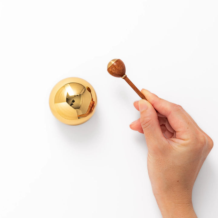 Japanese meditation and prayer chime with golden dome bell and wooden striker for mindfulness rituals.