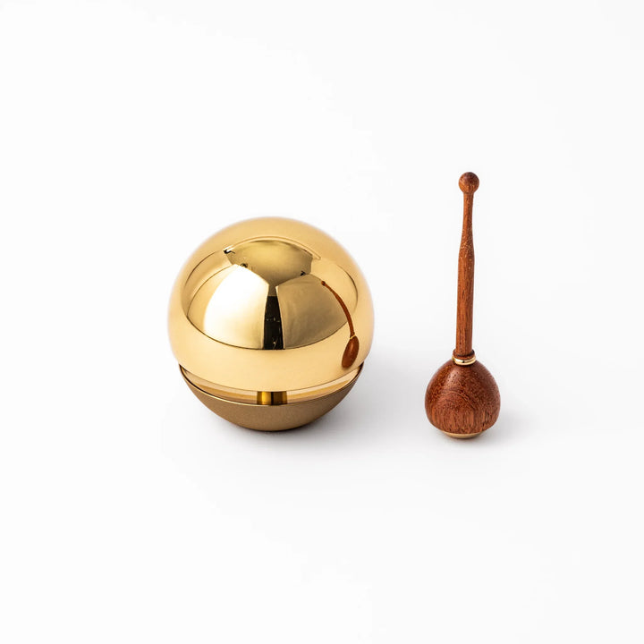 Japanese meditation and prayer chime with golden dome bell and wooden striker for mindfulness rituals.