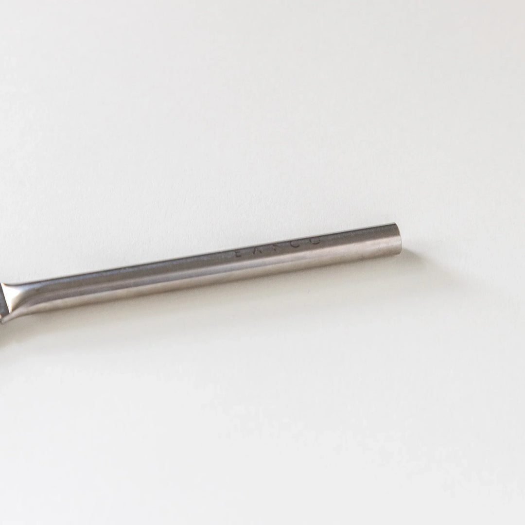 Close up view of the round handle on a Japanese stainless steel grater brush on white background