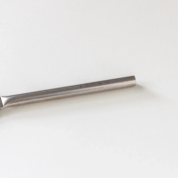 Close up view of the round handle on a Japanese stainless steel grater brush on white background