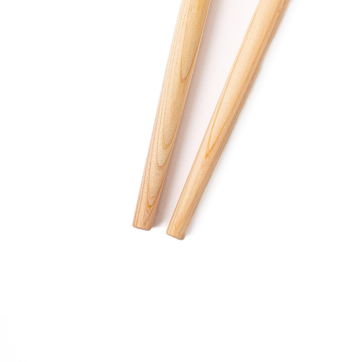 A pair of thick Japanese tempura cooking chopsticks made from light natural wood showcasing a minimalist and sturdy design