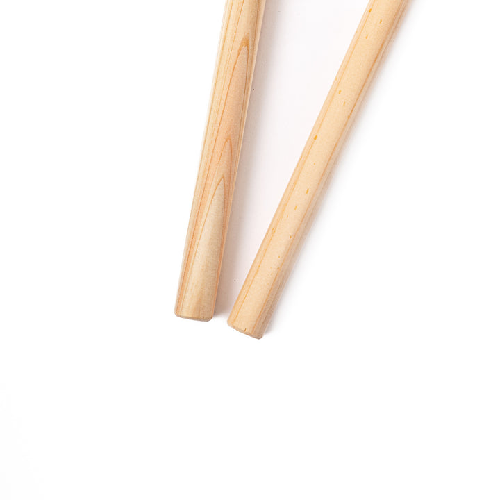 A pair of thick Japanese tempura cooking chopsticks made from light natural wood showcasing a minimalist and sturdy design
