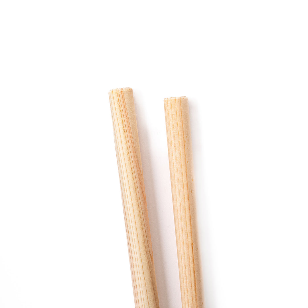 A pair of thick Japanese tempura cooking chopsticks made from light natural wood showcasing a minimalist and sturdy design