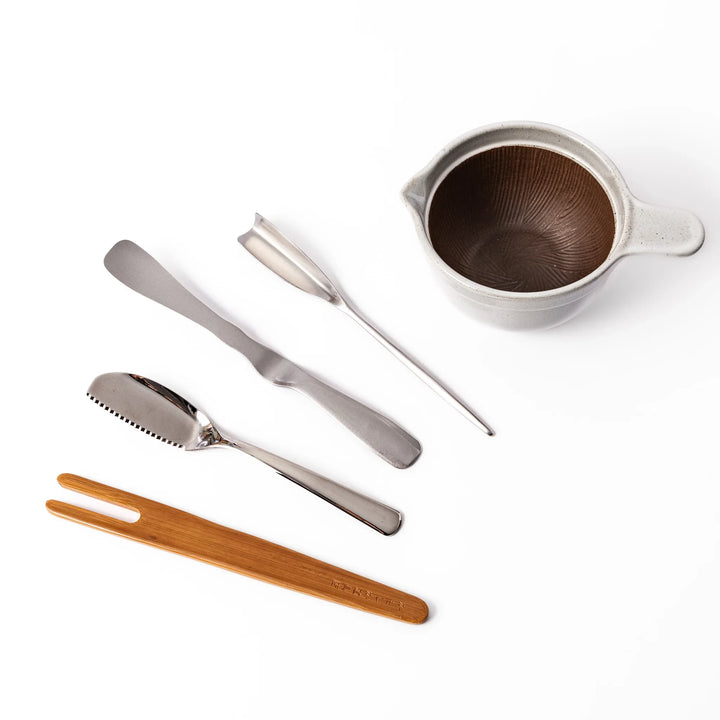 Japanese breakfast utensil set featuring stainless steel butter and fish knives, bamboo tongs, and a ceramic mortar bowl
