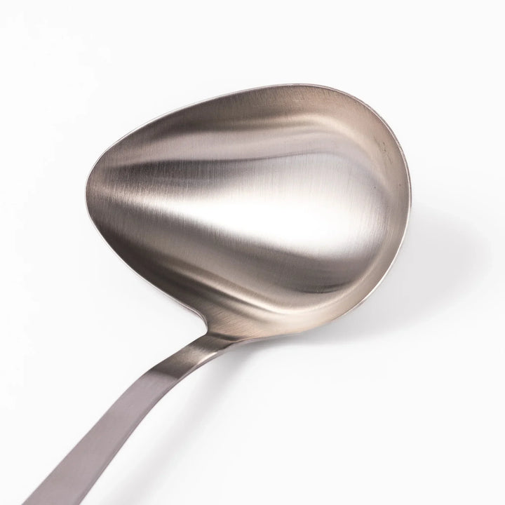 Japanese stainless steel soup ladle with long handle and deep curved bowl for serving soups and stews.