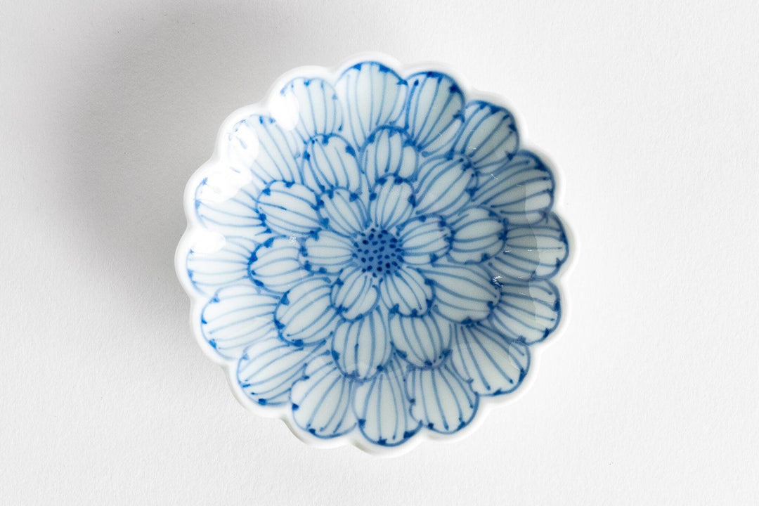 Blue and white porcelain sauce dish with scalloped rim featuring a detailed hand painted chrysanthemum petal pattern