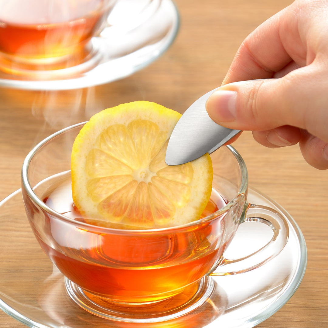 Japanese fingertip tongs placing a fresh lemon slice into a cup of hot tea for a clean and elegant serving experience