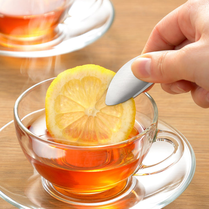 Japanese fingertip tongs placing a fresh lemon slice into a cup of hot tea for a clean and elegant serving experience