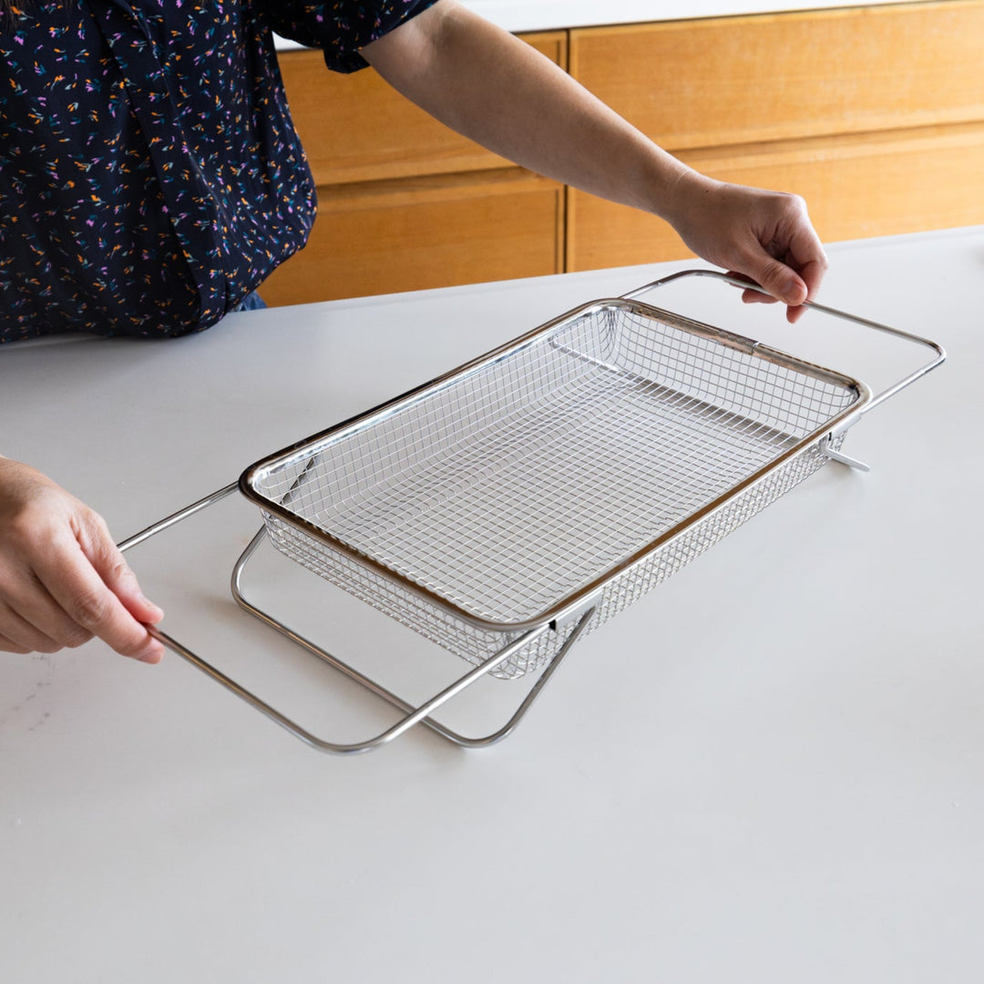 Nami from Just One Cookbook adjusting the expandable arms of a stainless steel draining basket on a kitchen counter