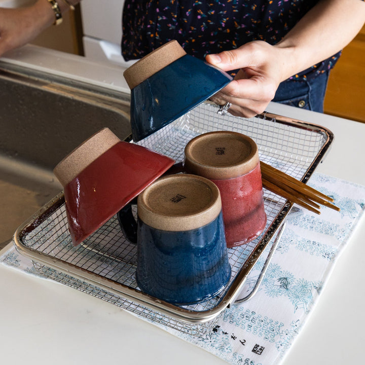 Nami from Just One Cookbook placing ceramic mugs and bowls on a stainless steel draining basket beside a kitchen sink