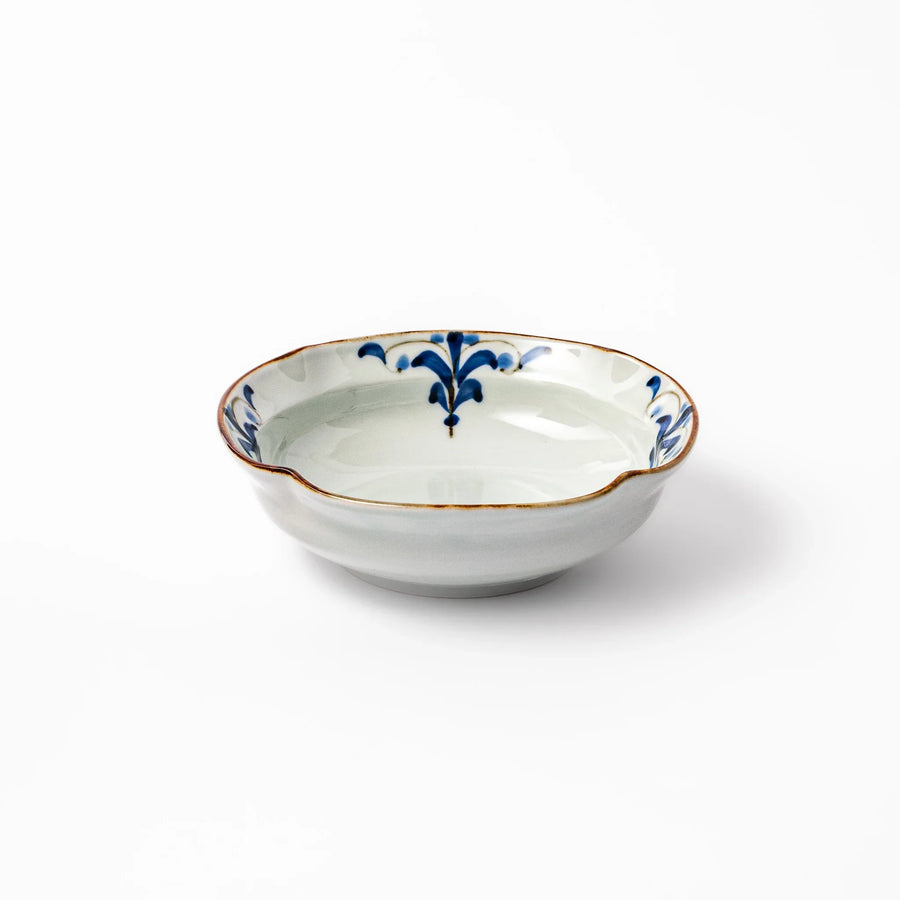 White ceramic cereal bowl with a scalloped rim, decorated inside with blue leaf motifs and a brown-accented edge.