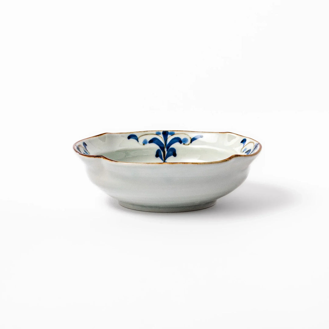 White ceramic cereal bowl with a scalloped rim, decorated inside with blue leaf motifs and a brown-accented edge.