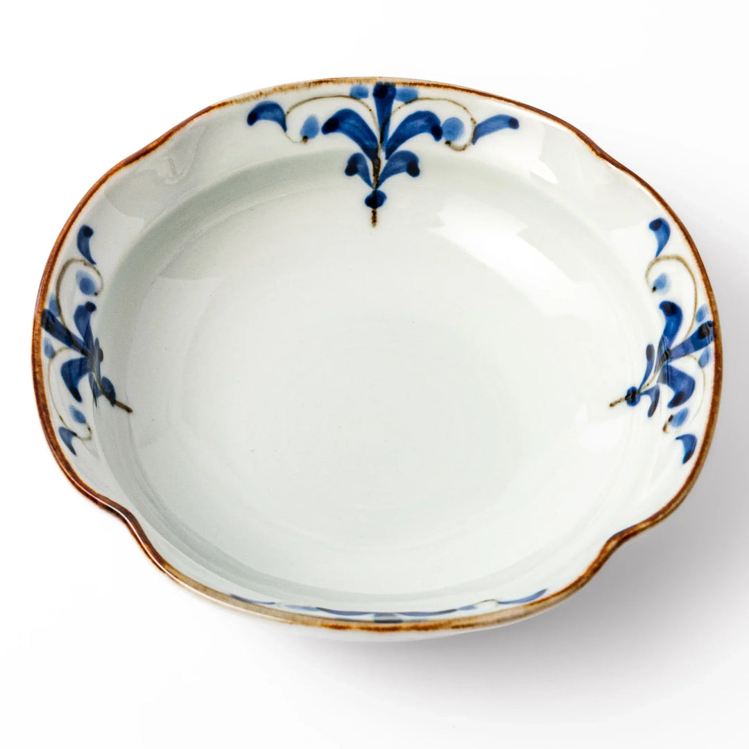 White ceramic cereal bowl with a scalloped rim, decorated inside with blue leaf motifs and a brown-accented edge.
