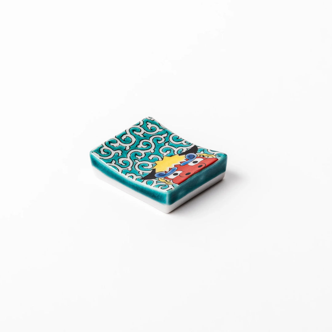 Rectangular Japanese ceramic chopstick rest with red lion dance motif and green swirl background for dining.