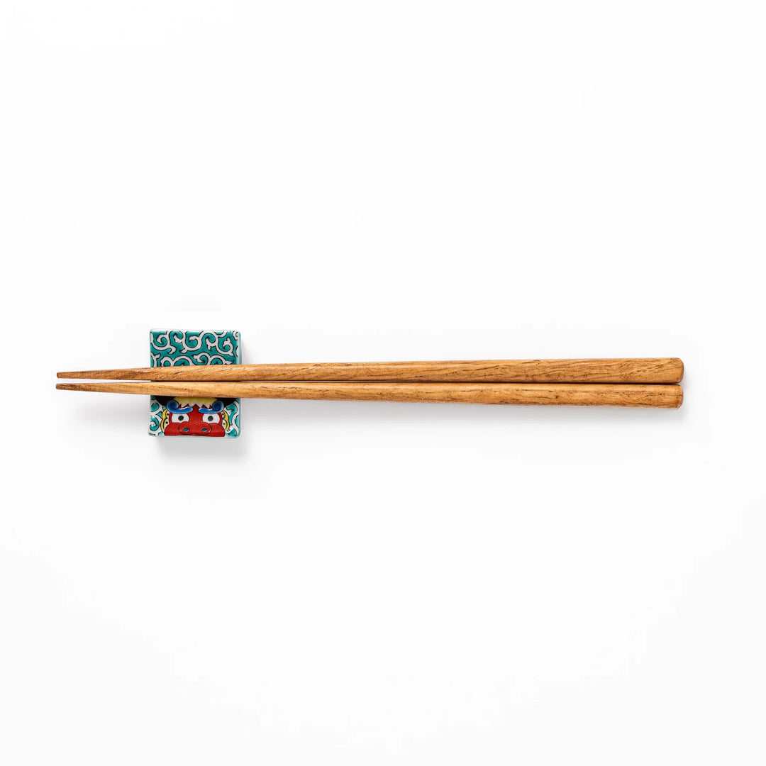 Rectangular Japanese ceramic chopstick rest with red lion dance motif and green swirl background for dining.