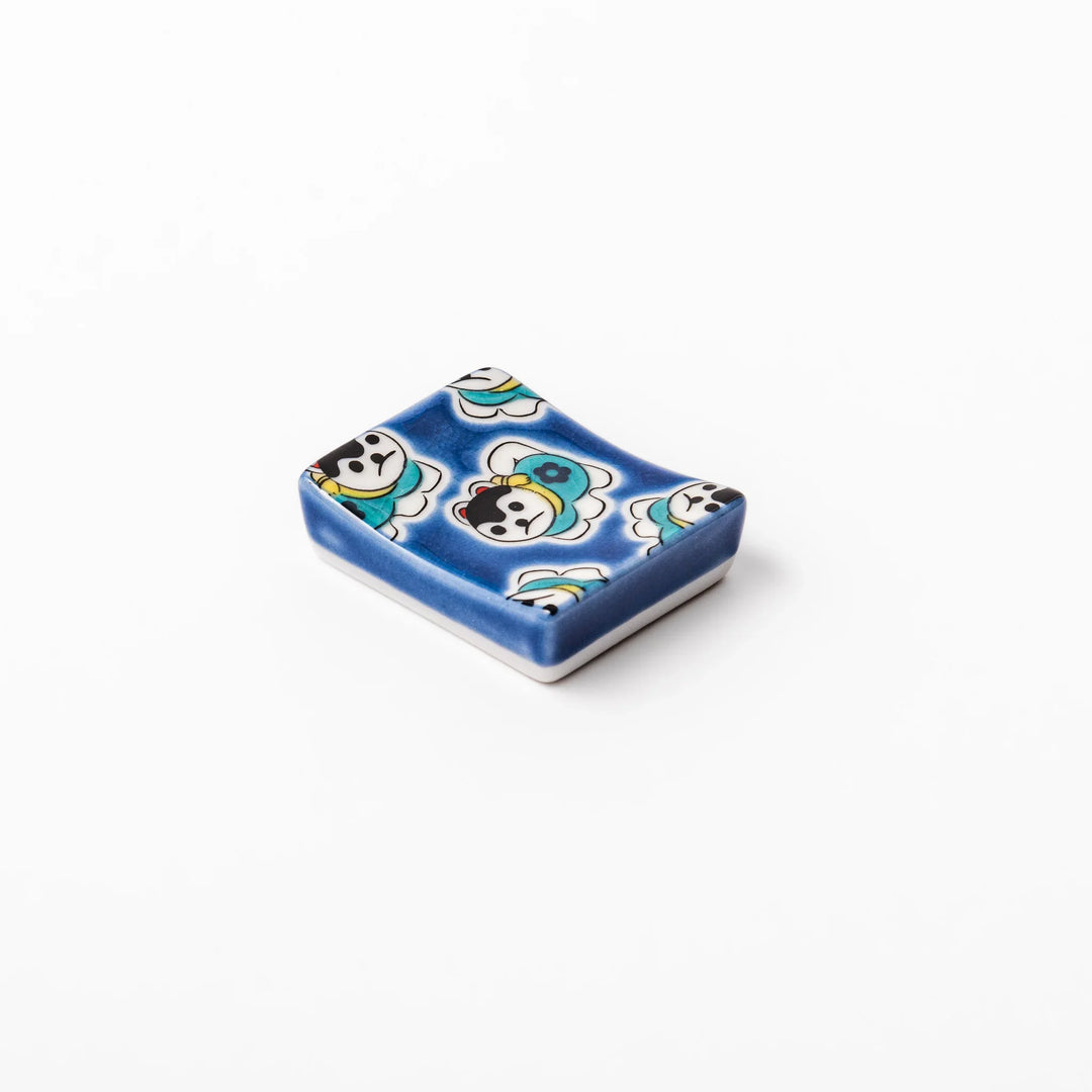 Rectangular Japanese ceramic chopstick rest with deep blue background and playful lucky dog motifs.
