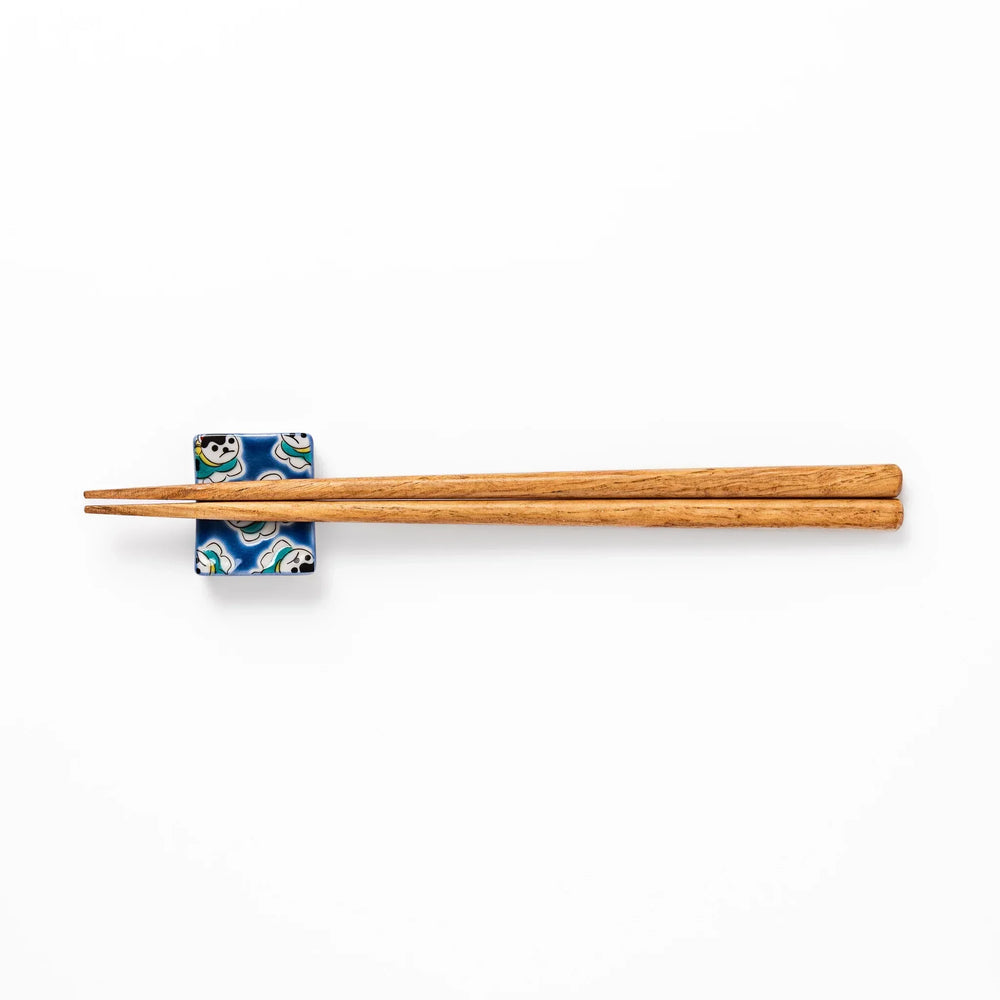 Rectangular Japanese ceramic chopstick rest with deep blue background and playful lucky dog motifs.