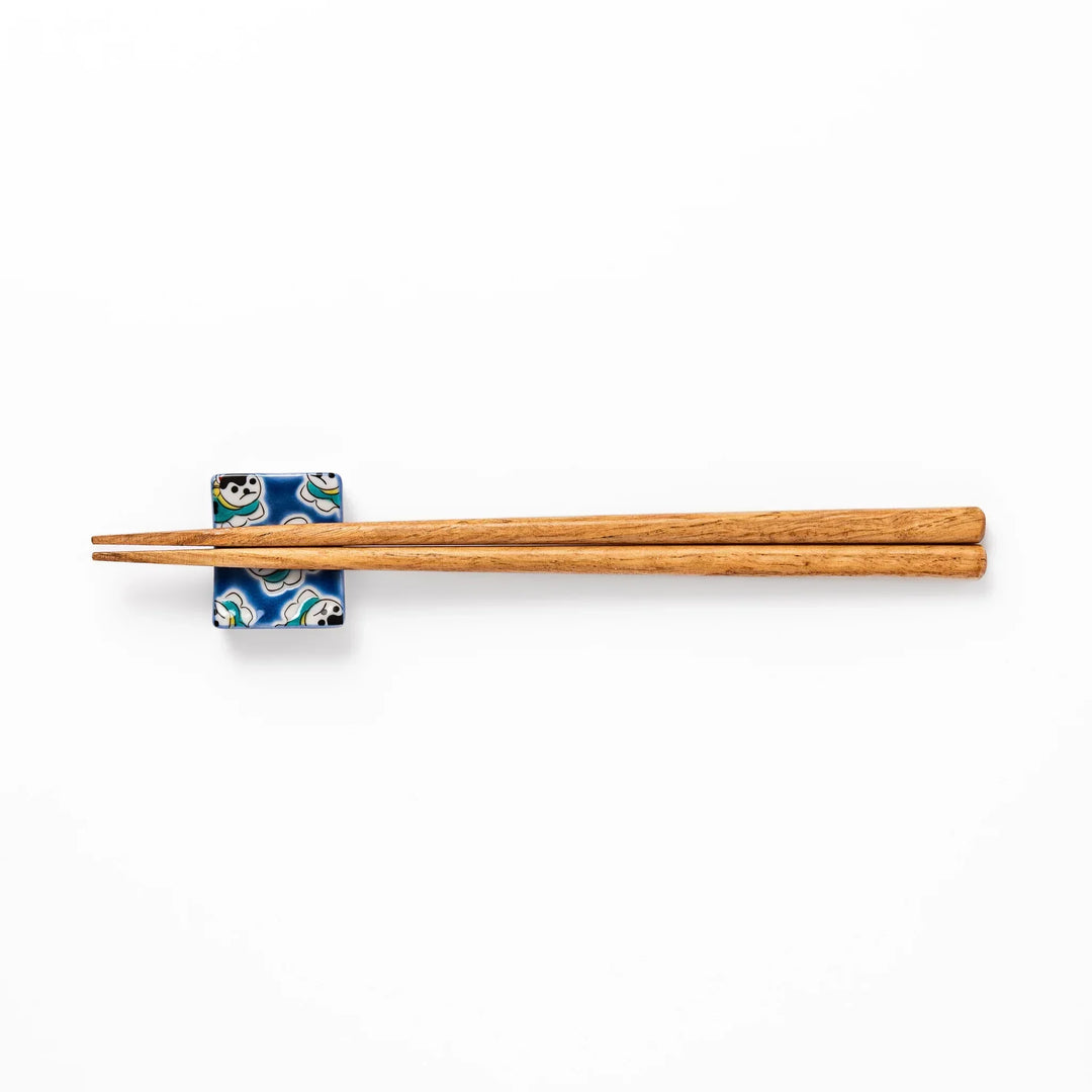 Rectangular Japanese ceramic chopstick rest with deep blue background and playful lucky dog motifs.
