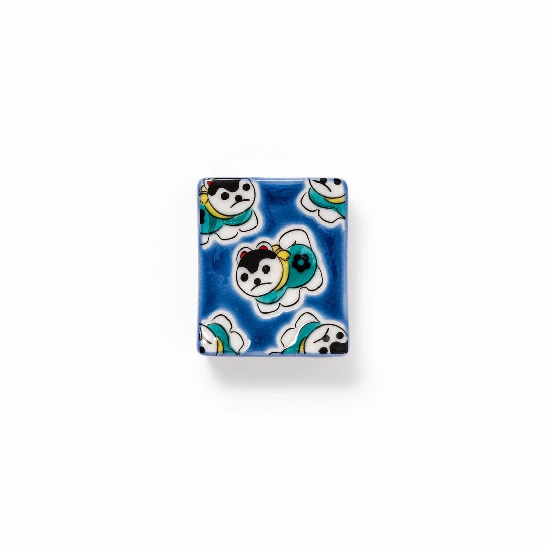 Rectangular Japanese ceramic chopstick rest with deep blue background and playful lucky dog motifs.