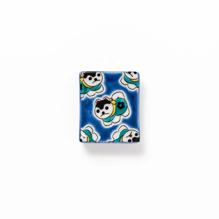 Rectangular Japanese ceramic chopstick rest with deep blue background and playful lucky dog motifs.