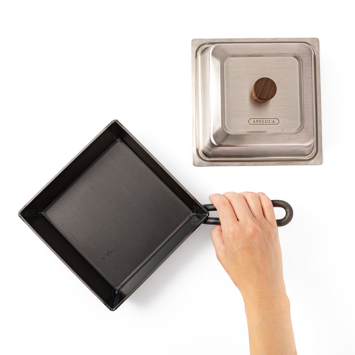 Nami from JOC holding handle of Japanese Luxe Carbon Steel Deep Pan beside stainless steel lid top view