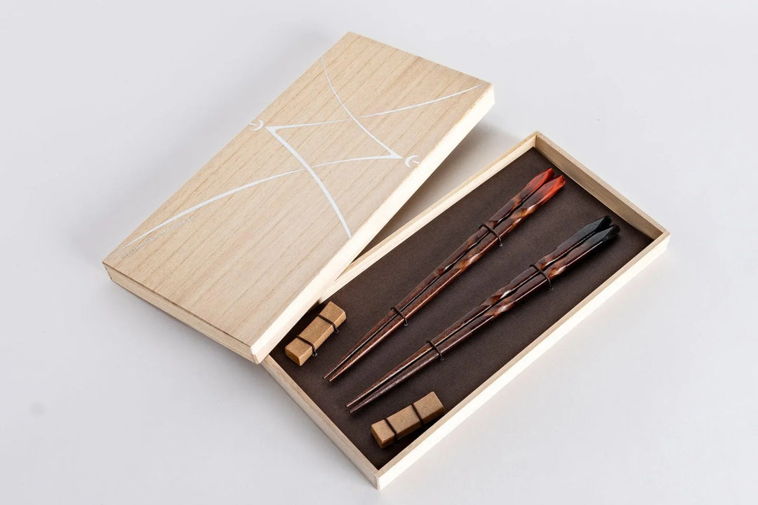 Japanese wooden chopsticks with carved feather design in a gift box with matching rests displayed on a white background