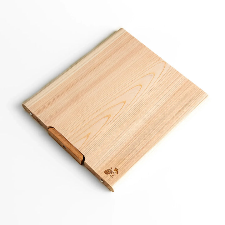 Medium Hinoki wood cutting board with natural grain, side handle, engraved motif, and smooth finish, crafted in Japan
