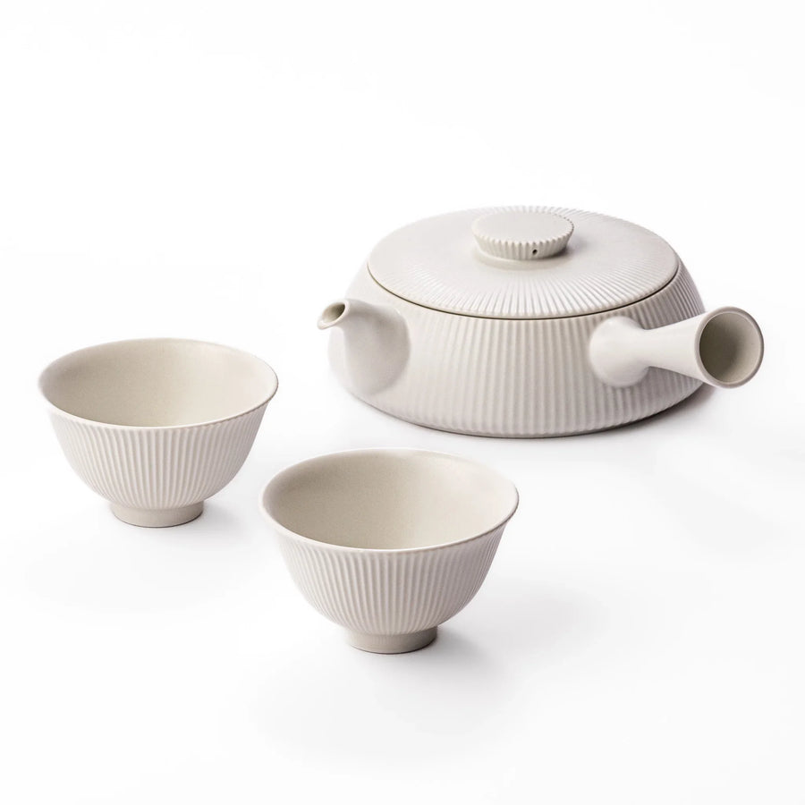 Minimalist Japanese tea set with ribbed white kyusu teapot and two cups for serene modern tea enjoyment.
