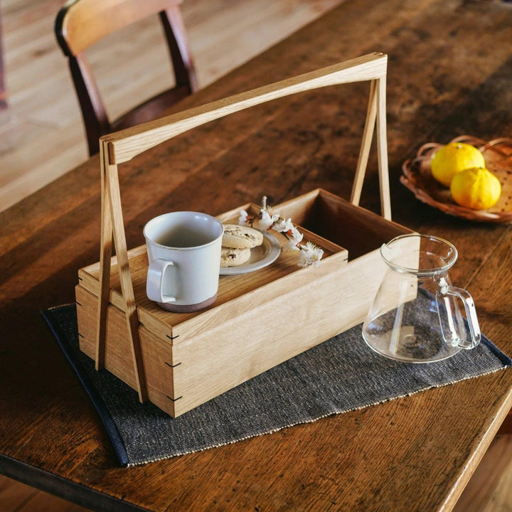 Japanese wooden okamochi storage caddy with removable tray used for coffee and snacks on rustic wooden table