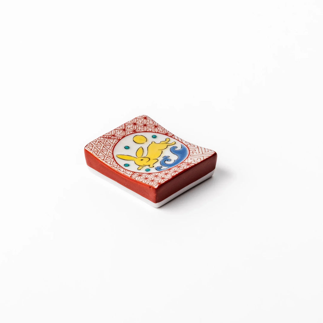 Rectangular Japanese ceramic chopstick rest with red geometric pattern and moon rabbit motif for charm.