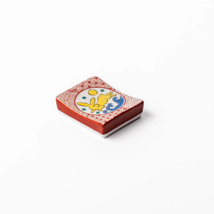 Rectangular Japanese ceramic chopstick rest with red geometric pattern and moon rabbit motif for charm.