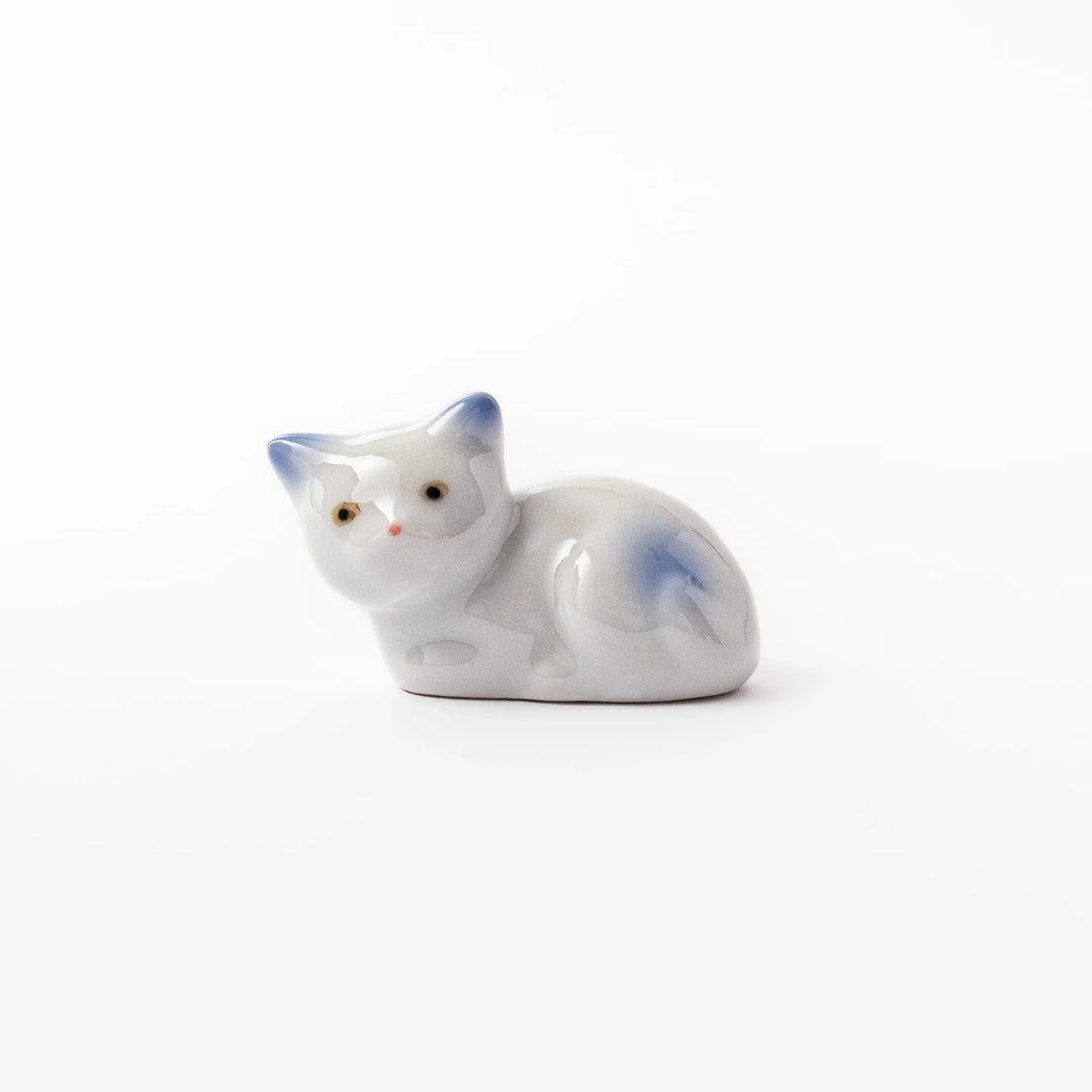 White ceramic chopstick rest shaped like a reclining cat with soft blue accents and a glossy finish.