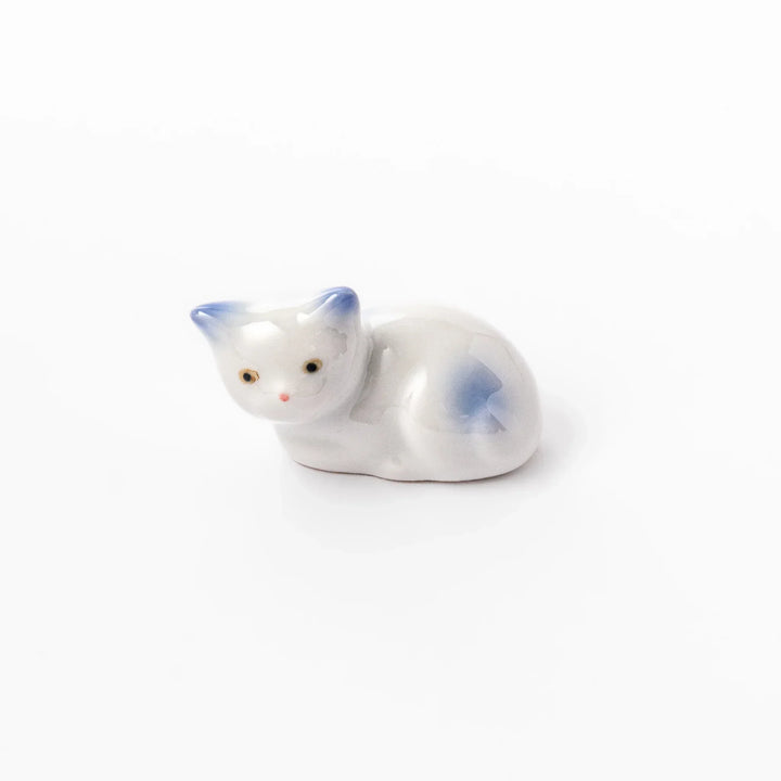 White ceramic chopstick rest shaped like a reclining cat with soft blue accents and a glossy finish.