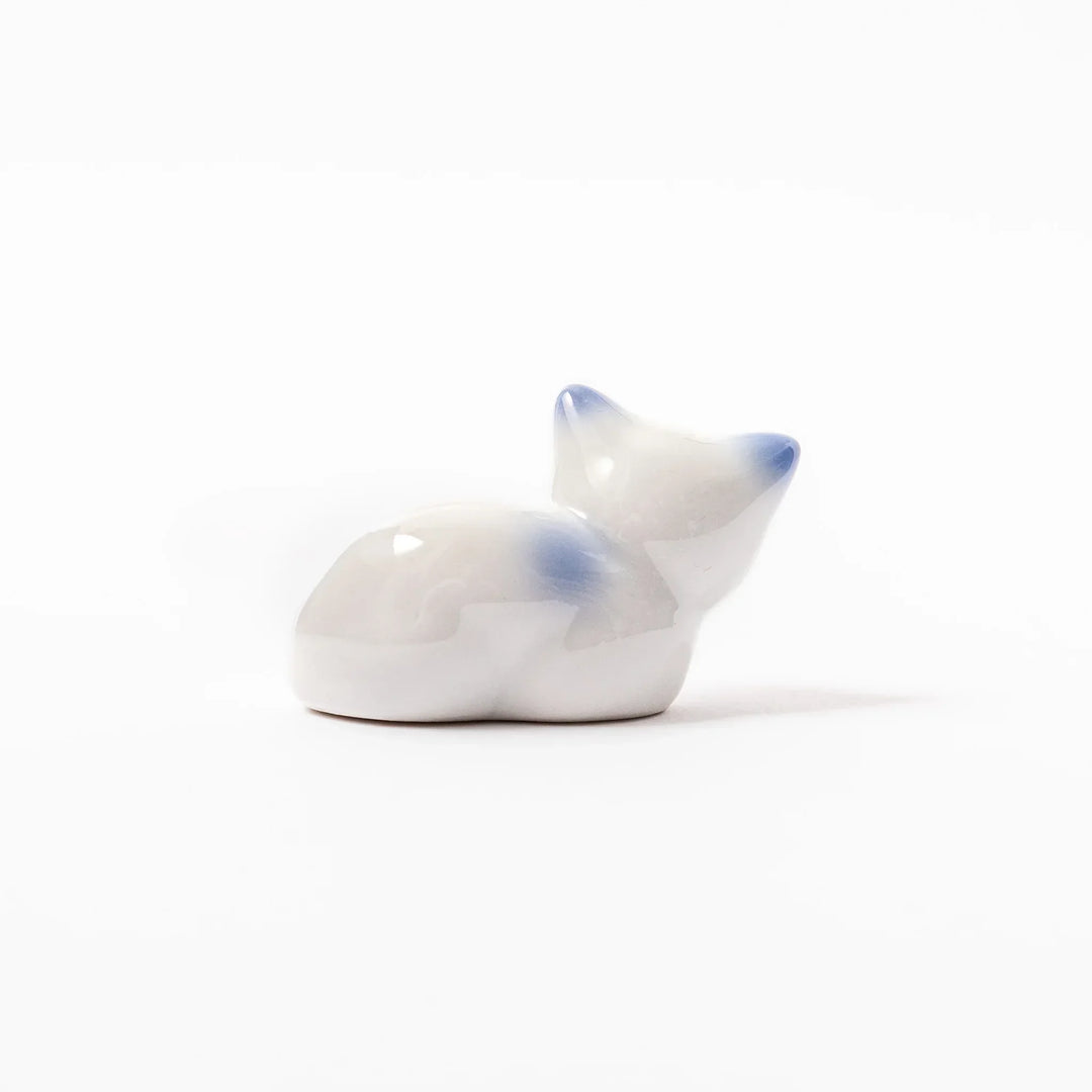 White ceramic chopstick rest shaped like a reclining cat with soft blue accents and a glossy finish.
