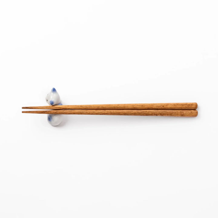 White ceramic chopstick rest shaped like a reclining cat with soft blue accents and a glossy finish.