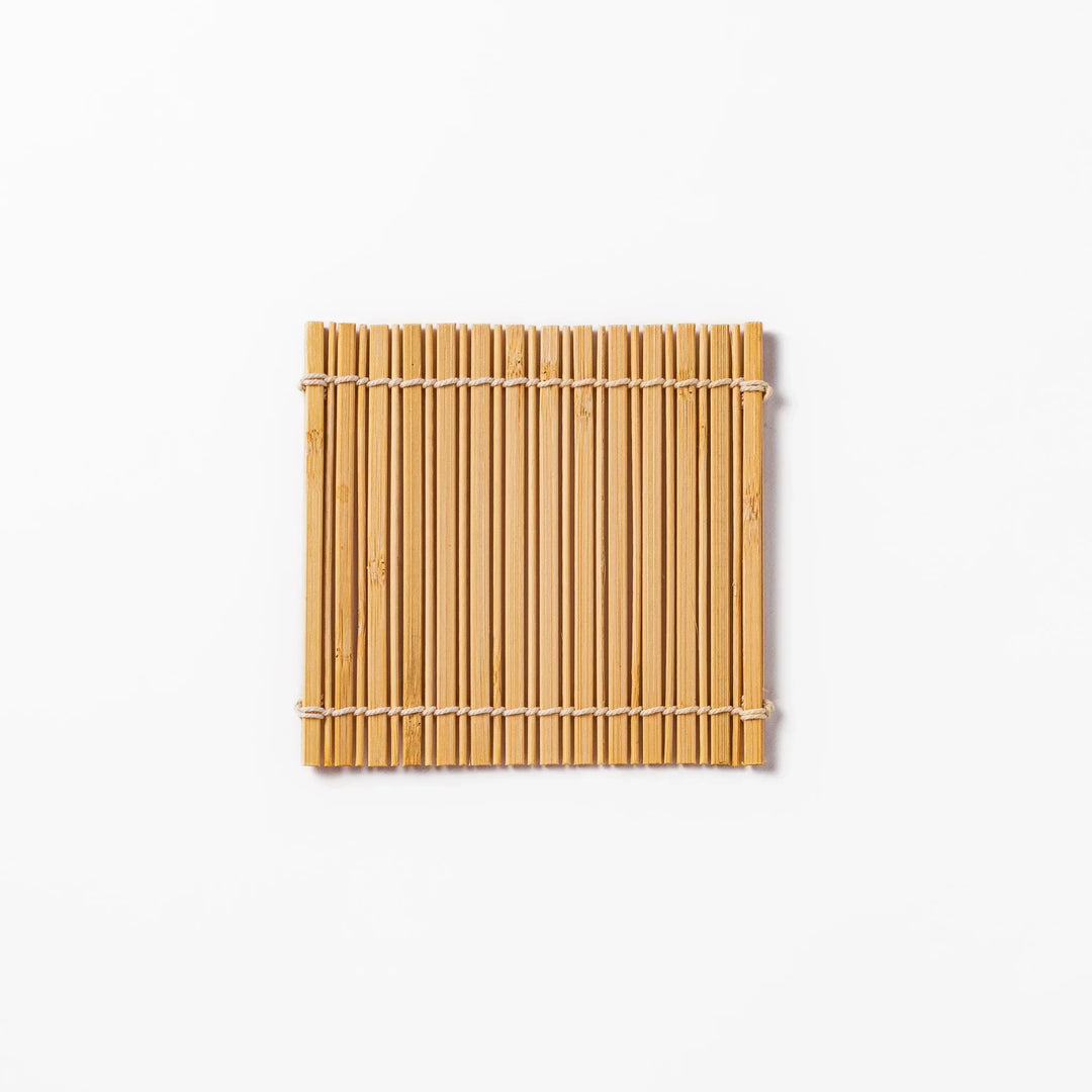Natural bamboo coaster with vertical slats and white cord ties for warm organic Japanese table style.