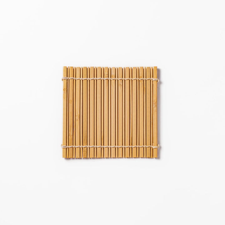 Natural bamboo coaster with vertical slats and white cord ties for warm organic Japanese table style.