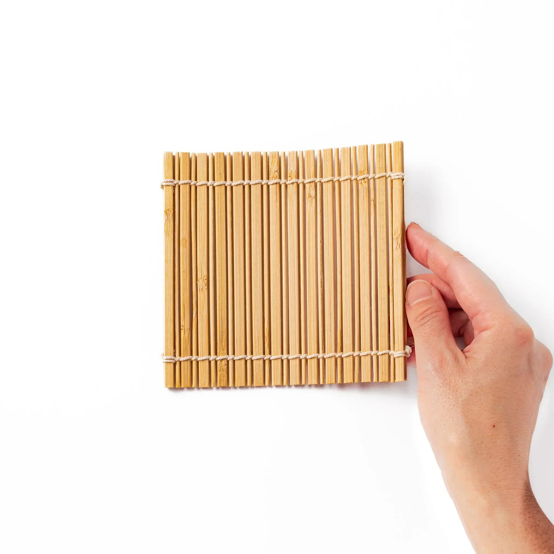 Natural bamboo coaster with vertical slats and white cord ties for warm organic Japanese table style.