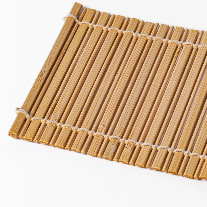 Natural bamboo coaster with vertical slats and white cord ties for warm organic Japanese table style.