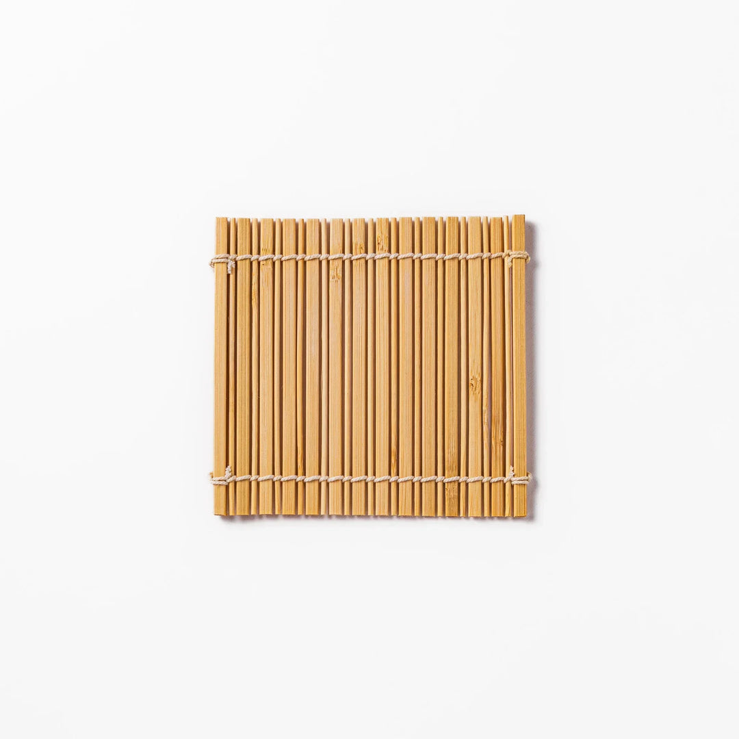 Natural bamboo coaster with vertical slats and white cord ties for warm organic Japanese table style.