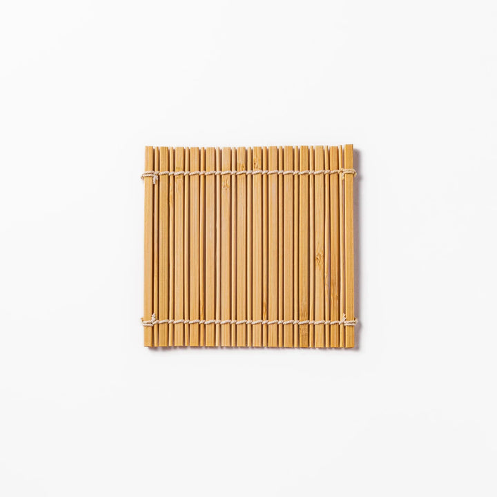 Natural bamboo coaster with vertical slats and white cord ties for warm organic Japanese table style.