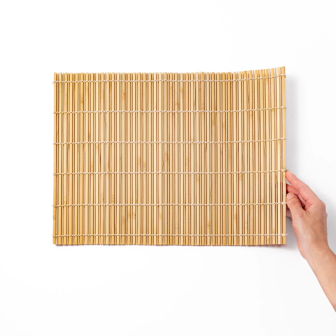 Natural bamboo table mat with vertical slats and white cord binding for earthy Japanese table settings.