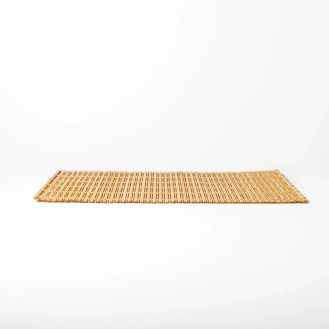 Natural bamboo table mat with vertical slats and white cord binding for earthy Japanese table settings.