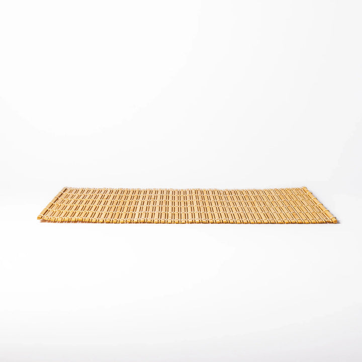 Natural bamboo table mat with vertical slats and white cord binding for earthy Japanese table settings.