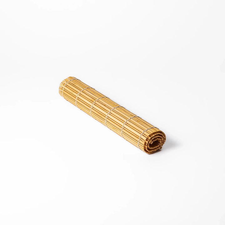 Natural bamboo table mat with vertical slats and white cord binding for earthy Japanese table settings.