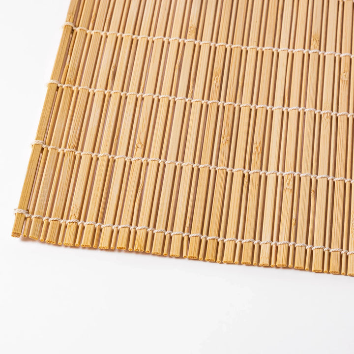 Natural bamboo table mat with vertical slats and white cord binding for earthy Japanese table settings.