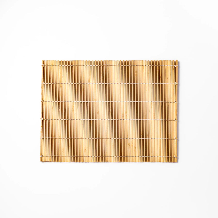 Natural bamboo table mat with vertical slats and white cord binding for earthy Japanese table settings.