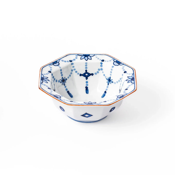 White octagonal dessert bowl with blue floral garland and red rim featuring fine geometric detailing.