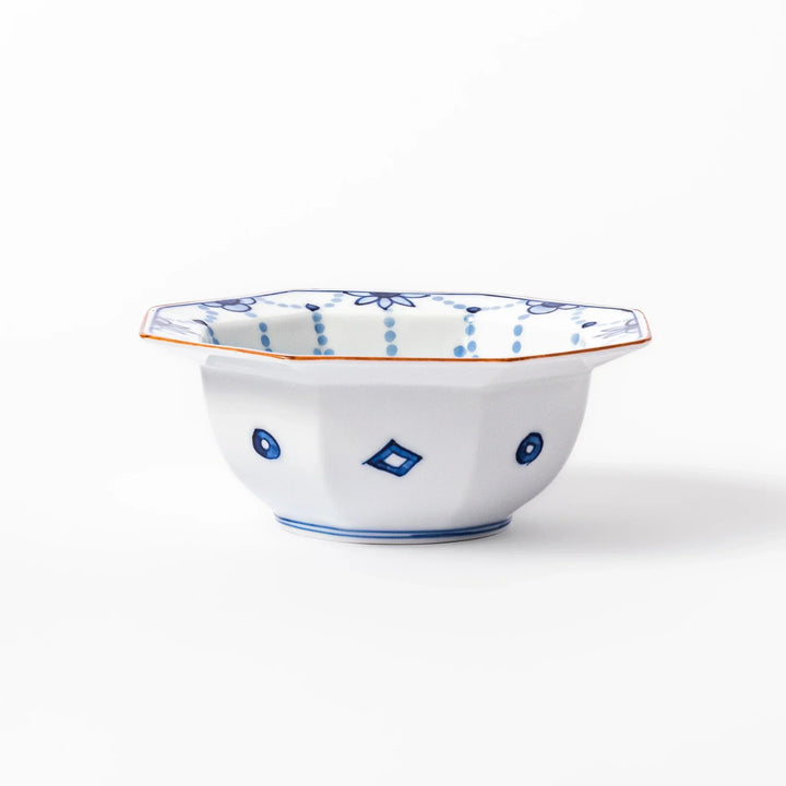 White octagonal dessert bowl with blue floral garland and red rim featuring fine geometric detailing.